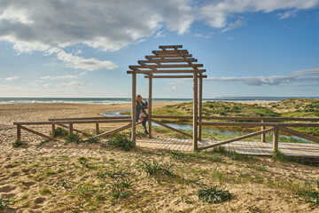 Woman daydreaming at wooden arch entrance to beach
