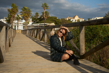 Woman relaxing on wooden boardwalk near beach