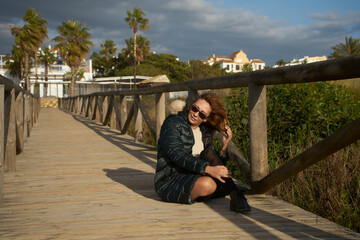 Woman relaxing on boardwalk, palm trees swaying in wind