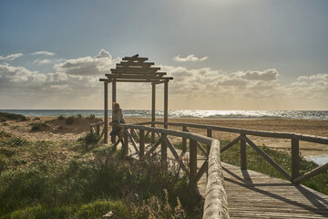 Woman contemplating ocean from boardwalk at sandy beach