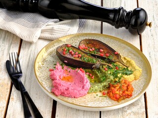 A delightful plate presents roasted eggplant adorned with pomegranate, accompanied by pink, green,...