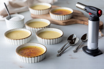 Ramekins of homemade Creme Brulee with a torch.