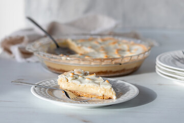 A close up of a serving of custard pie with the remaining pie in behind.