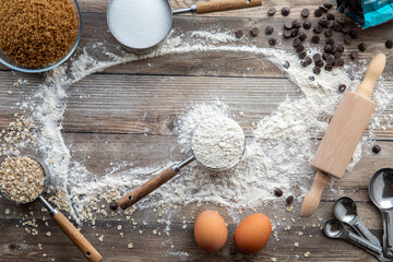 Baking ingredients scattered around on a rustic wooden table.