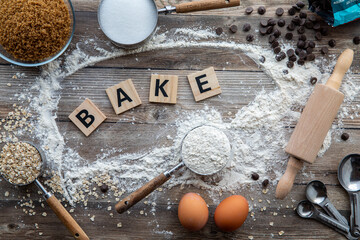 A baking background concept with the word bake on wooden tiles in the middle.