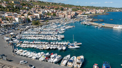 Aerial closeup of the marina of Aci Trezza, in province of Catania, Sicily, Italy. It's a tourist destination on the Mediterranean Sea. There are many boats anchored there this sunny summer morning. © Stefano Tammaro