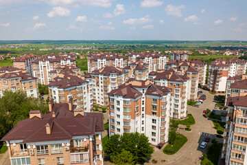 Fototapeta premium Top view of urban developing city landscape with tall apartment buildings and suburb houses. Drone aerial photography.