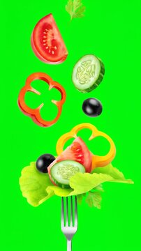 Salad ingredients levitating over silver fork. Slices of tomato, cucumber, bell peppers, and olives  against green screen background for food commercial. Lockdown vertical shot.