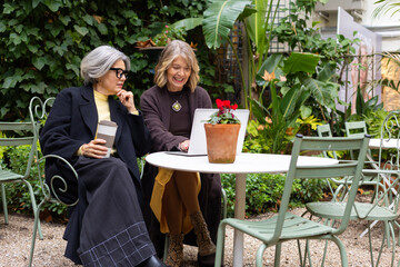 Senior friends enjoying technology and friendship in outdoor cafe