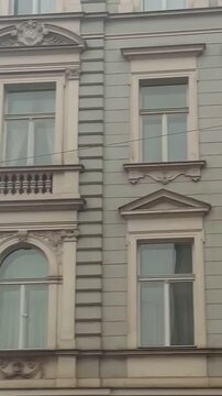 historic facades under overcast gray sky, rooftop silhouettes and tram wires cross scene, quiet melancholic city atmosphere during cold season Vertical shot taken on mobile device