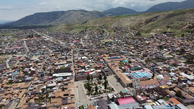 aerial drone view over peru town showing dense colorful rooftops, central plaza and market, straight