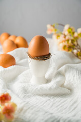 Easter spring background. Egg in a ceramic egg holder stand with flowers. Minimalistic