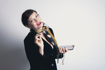 A woman wearing glasses and a yellow scarf is holding a cell phone. She is smiling and she is happy