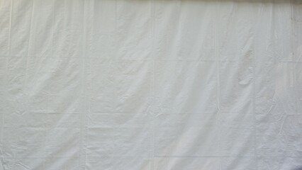 The white canvas is wrinkled and creased. White fabric texture with wrinkled texture. Wrinkles and texture for background or design element, texture, and background.