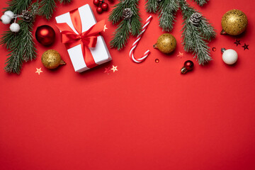 Red and white Christmas decorations and gifts on red background.