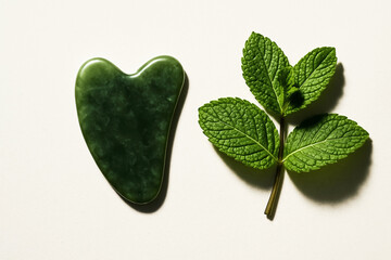 Heart Shaped Green Jade Gua Sha Tool and Fresh Mint Sprig for Natural Skincare