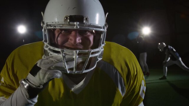 Medium portrait of strong, fearless Caucasian male American football player in protective gear putting on mouthguard, roaring and beating on helmet to intimidate rival team opponents