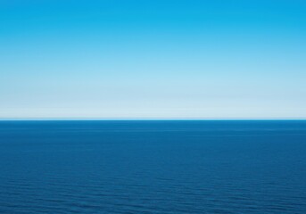 Fototapeta premium A breathtaking, ultra-wide panoramic seascape showing the massive blue ocean meeting a clear summer sky at the distant, infinite horizon line, blue, reflective, liquid