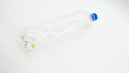 Plastic bottle on a plain surface with visible dirt and debris