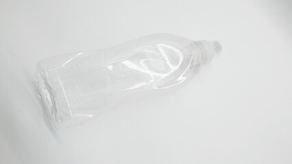 Clear plastic bottle lying on a white surface with reflections visible in light
