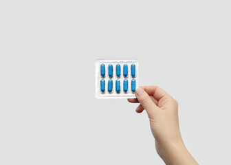 Hand holding a blister pack of blue medicine capsules