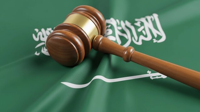 A wooden gavel rests on the waving flag of Saudi Arabia, symbolizing justice, law, and legal proceedings within the nation.