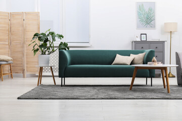 Stylish room with monstera houseplant and comfortable sofa. Interior design