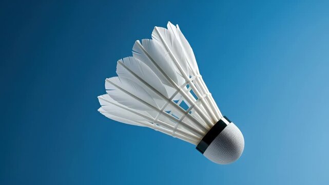 White badminton shuttlecock flying in the air on a clean blue background. Sequence showing a birdie in motion for sports and recreation concepts. Professional athletic equipment