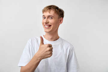 Happy young man gives a thumbs up in a casual pose, conveying positivity, confidence and friendly...