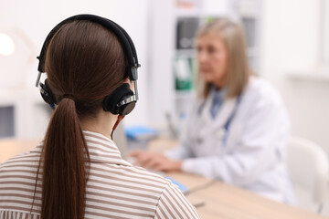 Patient with audiometric headphones undergoing hearing test in clinic, selective focus. Space for text © New Africa
