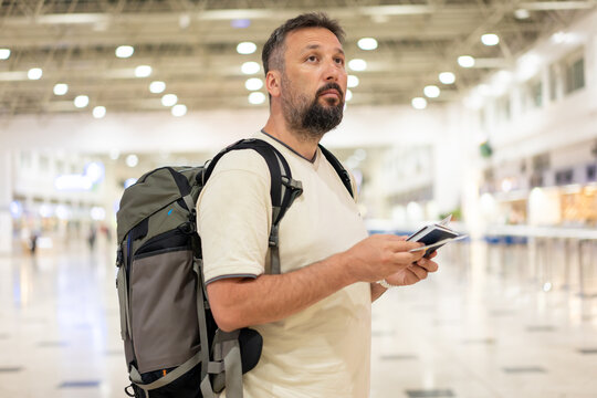 Traveler in airport on his phone checking the directions for his flight. High quality photo