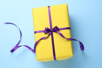 Beautiful gift with bow on light blue background, top view