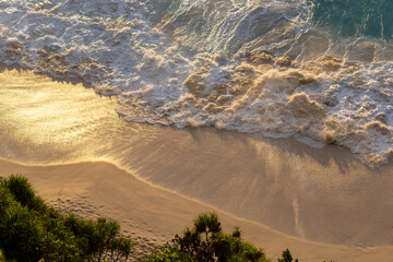 Aerial Top-Down View of a Beach with Gentle White Foamy Waves at Golden Hour. High quality photo