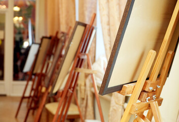Wooden easels lined up in a bright, airy studio space, showcasing empty canvases ready for artistic expression and creativity, inviting inspiration and imagination