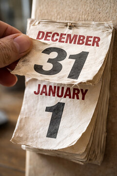 Hand tearing calendar page from December 31 to January 1