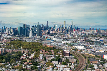 A massive aerial panorama captures the sprawl of New York City, with the residential neighborhoods leading toward the dense Midtown Manhattan skyline.