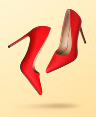 Red high heel shoes in air on beige gradient background