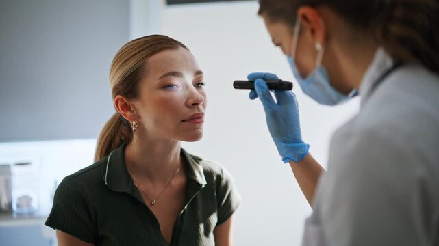 Neurologist testing woman eyes reflexes during checkup. Doctor checking health