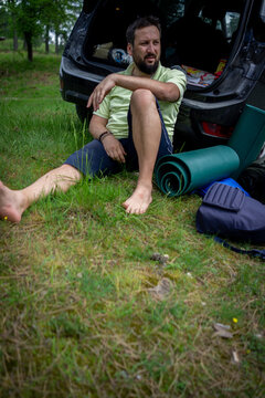 Casual man resting in the open trunk of a car in the woods. High quality photo