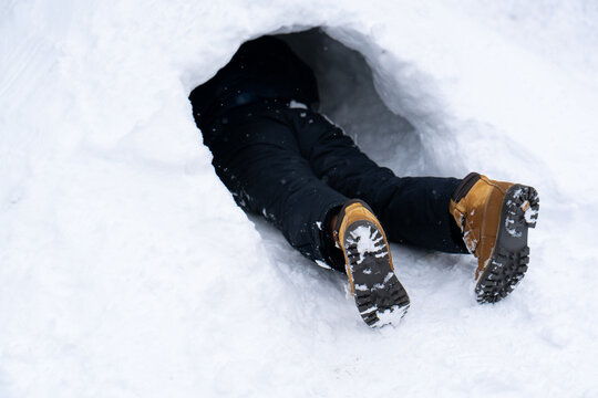 Person Partially Buried in Snow Cave - Only Legs Visible. High quality photo