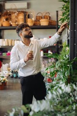 Fototapeta premium Man choosing green plants in flower shop