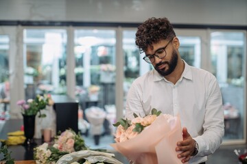 Male florist creating a beautiful flower bouquet in shop