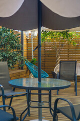 patio furniture terrace brown wooden deck cozy outdoor seating area under a large grey umbrella in a garden cafe with copy space for banner design concept of leisure, lifestyle, hospitality