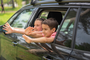 Brother and Sister Laughing and Reaching out of Car Window. High quality photo