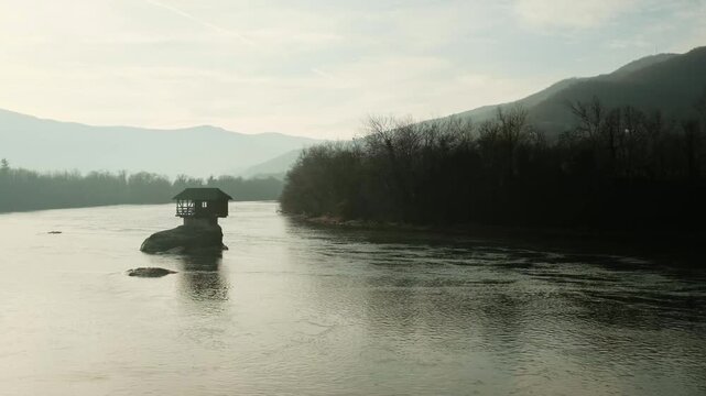 Small popular wooden House on the Drina River near Bajina Basta, Serbia country. Iconic wooden house standing on a rock in the middle of the river, surrounded by mountains and calm water