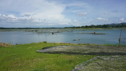 Traditional fish farms on a large lake with mountains and cloudy sky background
