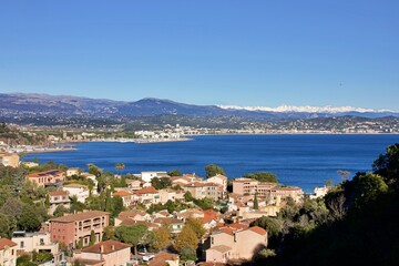 Obraz premium Stunning panoramic winter landscapes of the French Riviera, featuring the coastal towns of Cannes and Théoule-sur-Mer. The Mediterranean Sea contrasts beautifully with the snow-covered mountains