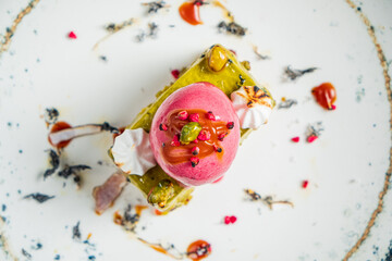 A colorful dessert showcases layers of texture and flavor, topped with vibrant sorbet and garnishes