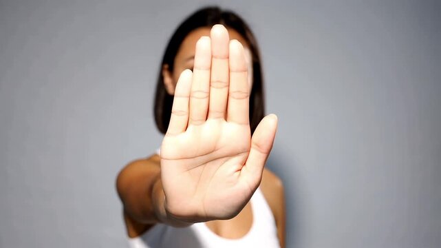 Young woman showing a stop gesture with her palm forward to the camera standing