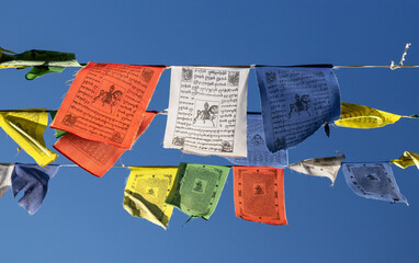 Tibetan prayer flags hang in a Buddhist temple under a clear blue sky showcasing colors and designs of spirituality and culture